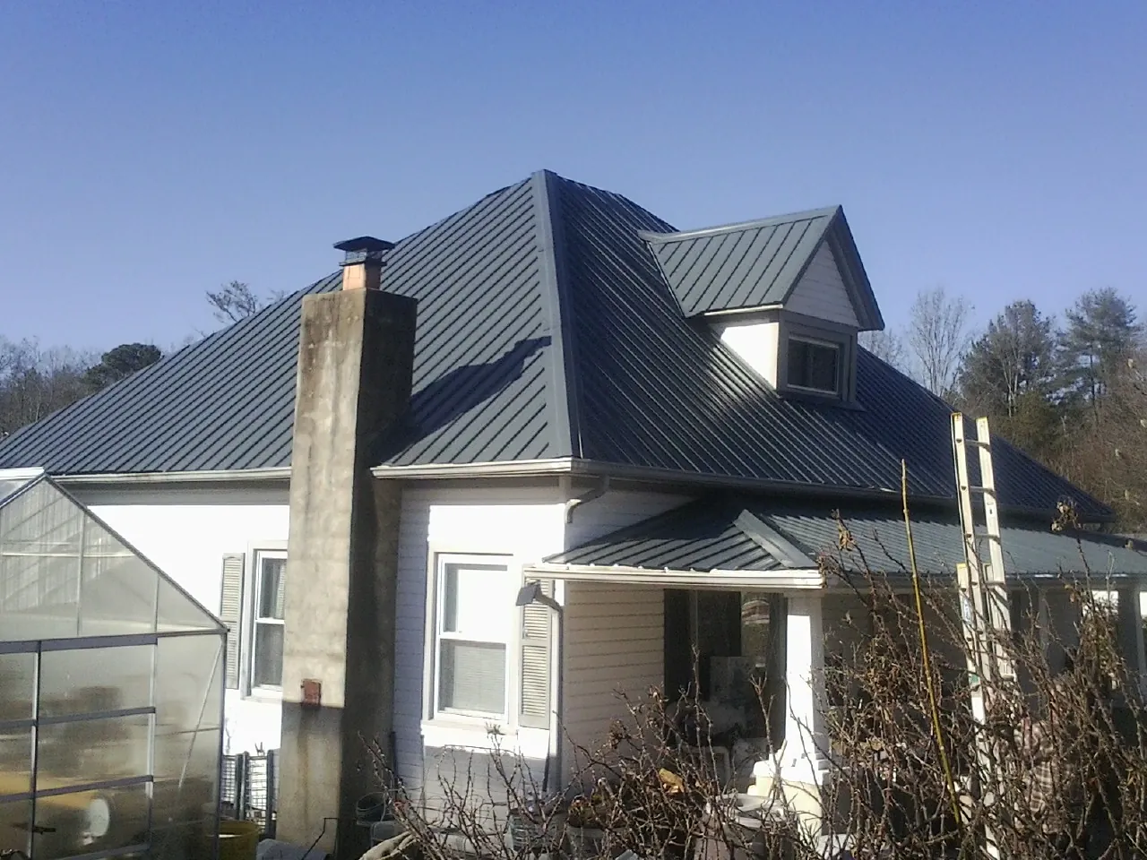 Dark blue standing seam metal roof on a white farmhouse with dormer — Slate & Tile Roof Repair by Roofing Brothers in Moorpark