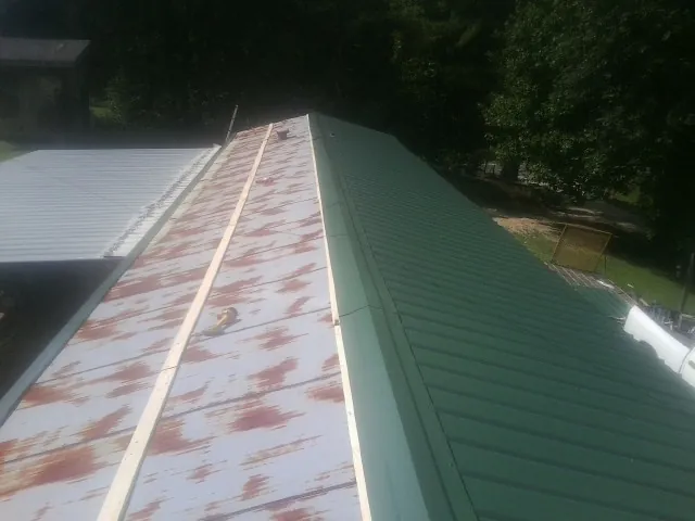 Old rusted panels beside newly installed green metal roofing — Wind Damage Roof Repair by Roofing Brothers in Moorpark