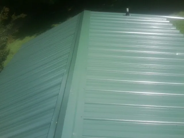 New green metal panels meeting at the ridge of a roof — Flat Roof Repair work by our crew in Moorpark
