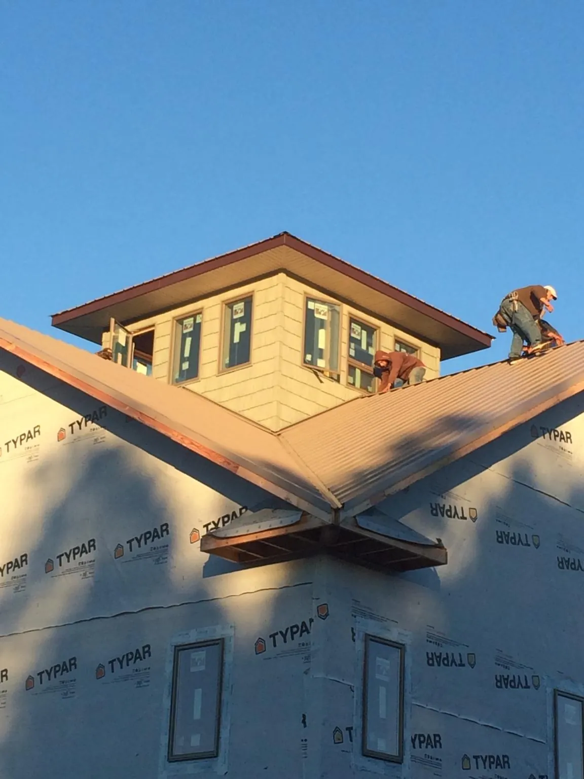 Roofers working around a rooftop cupola on a new metal roof at sunset — Roof Waterproofing in Moorpark by Roofing Brothers